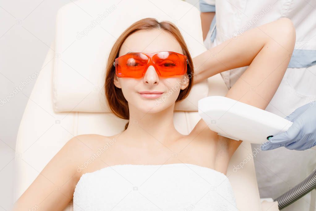 Underarm skin care. Woman on procedure of laser hair removal in medical office