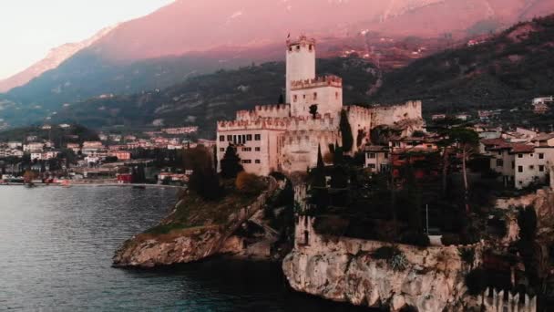 Jezioro Lago Di Garda - widok na miejscowości Malcesine. Stary zamek na skale Włochy. Lotnicze wideo zachód słońca — Wideo stockowe