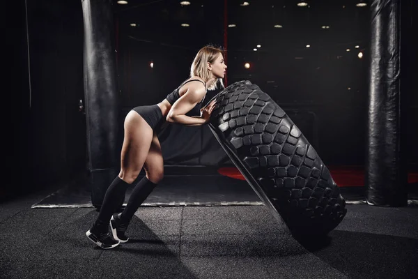 Trainingskonzept. Sportliche Fitness junge Frau kippt Reifenrad um — Stockfoto