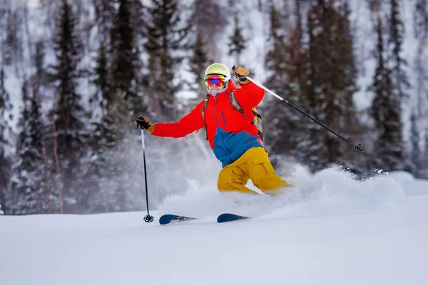 Kasklı ve maskeli genç adam ağaçların arkasında kayak yapıyor. — Stok fotoğraf