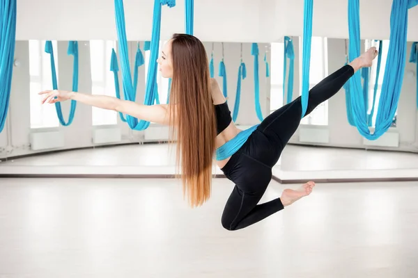 Yoga de mouche aérienne dans le gymnase blanc. Jeunes belles femmes pratiquant des pilates étirant dans l'hamac bleu — Photo