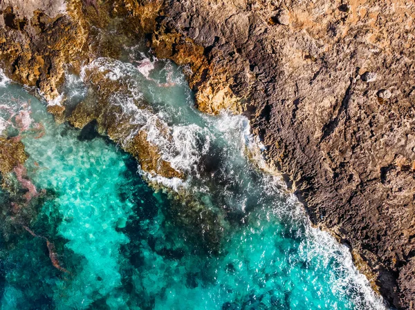 El agua clara azur golpea la costa rocosa de la playa de coral. Vista superior aérea — Foto de Stock