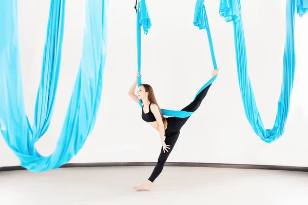 Ung kvinna som utför antigravitationsflygande yogaövning i vit studio. Begreppsmeditation — Stockfoto