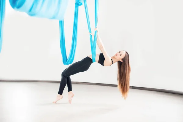 Flygflyga yoga i vitt gym. Unga vackra kvinnor tränar stretching pilates i blå hängmatta — Stockfoto