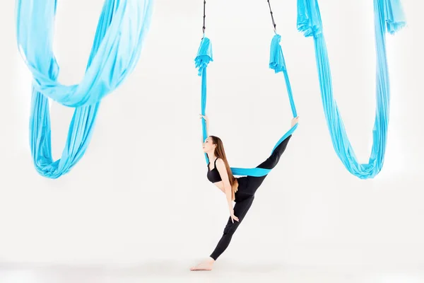 Unga vackra kvinnor gymnast i blå hängmatta. Flygflyga yoga i vit studio — Stockfoto