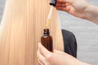 Yakından bir damla yağ alınır ve saç teli baş ampullerine uygulanır. Kuaför spa salonu kavramı