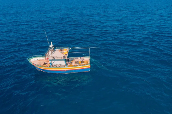 Fishing boat in blue sea water, fishermen set nets for fish