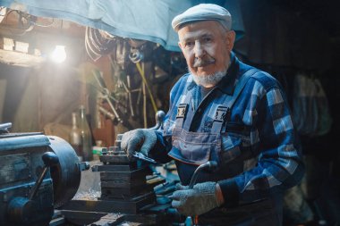 Metal için takım tezgahı üzerinde çalışan yaşlı yaşlı erkek turner mekanik