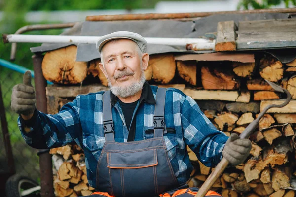 El hombre mayor sonriente es una herramienta de afilado para cultivar tierra de granja. Concepto agrícola — Foto de Stock