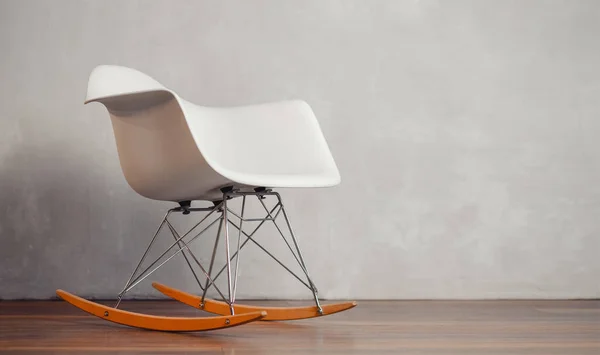 Gray rocking chair in white concrete room for copy space. Concept of minimalism