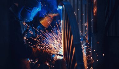 Profesyonel kaynakçı koruyucu maske metal üzerinde kaynak çalışmaları yapar. Endüstriyel işçi kavramı