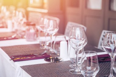 Restoran masa ayarı, şarap bardakları ve beyaz tabaklar. Işığın parıltısı