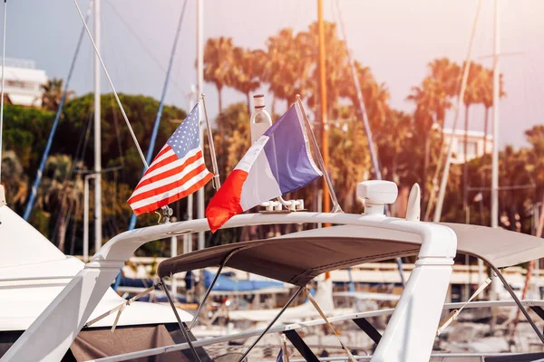 Banderas de primer plano de Francia y Estados Unidos en yate blanco con luz del sol — Foto de Stock
