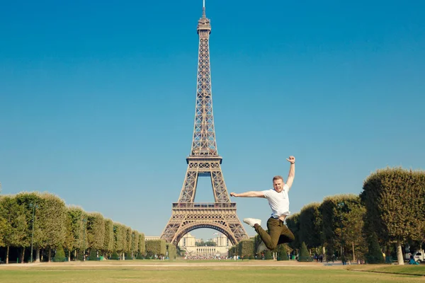 Torre Eiffel. O tipo saltou para o ar, de mãos dadas. Quente dia de outono ensolarado. Amarelo árvores Parque — Fotografia de Stock