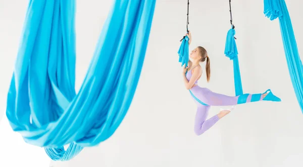 Vacker ung kvinna leende på att öva Aero fly yoga i vit Studio på blå hängmattor. Koncept stretching meditation, — Stockfoto