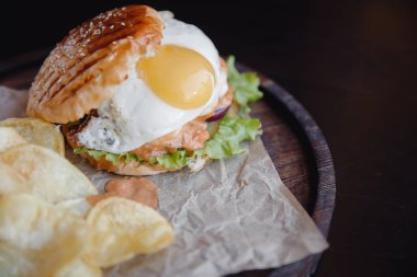 Kızarmış yumurtalı iştah açıcı burger, köfte, ızgara çörek. Patates cipsinin yanında. Fast food kavramı.