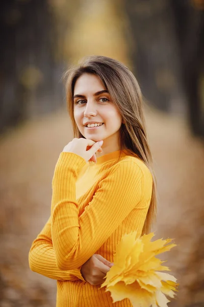 Retrato de menina bonita em suéter amarelo na floresta de outono com folhas de bordo — Fotografia de Stock