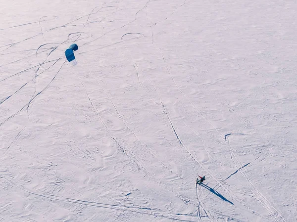 Snowkiting. Male athlete on mountain skiing with dreams kite free ride on frozen lake. Aerial view — Stock Photo, Image