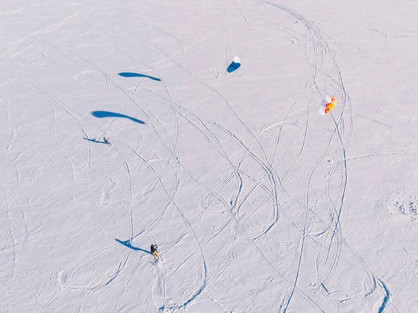 Snowkiting. Male athlete on mountain skiing with dreams kite free ride on frozen lake. Aerial view — Stock Photo, Image