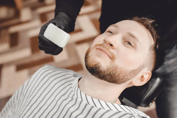 Il barbiere tratta la pelle di faccia dopo rasatura pericolosa con sapone da batteri, disinfezione in barbiere — Foto Stock