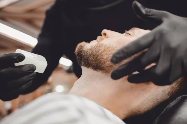 Kapper behandelt huid van gezicht na gevaarlijke scheren met zeep van bacteriën, desinfectie in Barbershop — Stockfoto