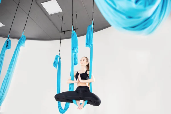 Ung kvinna som utför antigravitationsflygande yogaövning i vit studio. Begreppsmeditation — Stockfoto