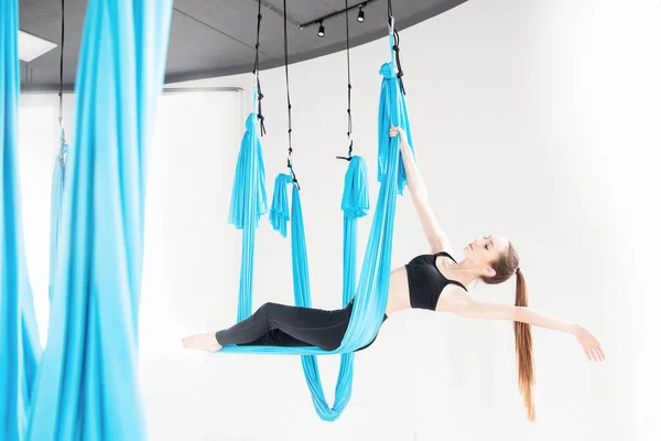 Wanita muda melakukan latihan yoga anti gravitasi di studio putih. Meditasi konsep — Stok Foto