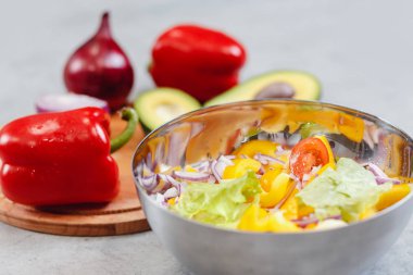 Taze sağlıklı salata için dilimlenmiş sebze ile Kase, arka planda malzemeler: avokado, biber, soğan, domates