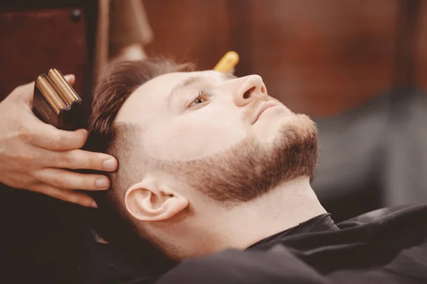 Barber snijdt zijn baard aan man in fauteuil — Stockfoto