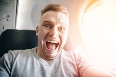 Uçaktaki yolcu, yükseklik ve uçuştan korkacak şekilde başını tutuyor. Çığlık ve ağlama ifadesi