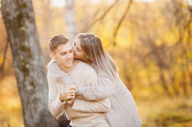 Sonbahar parkında, akçaağaç yapraklarıyla sevgili bir çift. Kız, güzel adama kulağına aşk ilanı fısıldıyor.