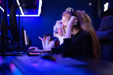Astar güzeli profesyonel oyuncu kazananı kulaklıkla bilgisayar oyunu oynayarak zafere seviniyor.