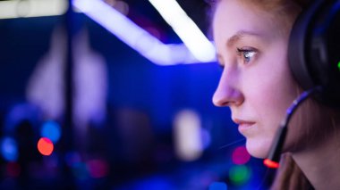 Streamer güzel kız profesyonel oyuncu gülümsemesi çevrimiçi oyunlar oynuyor kulaklıkla bilgisayar, neon rengi