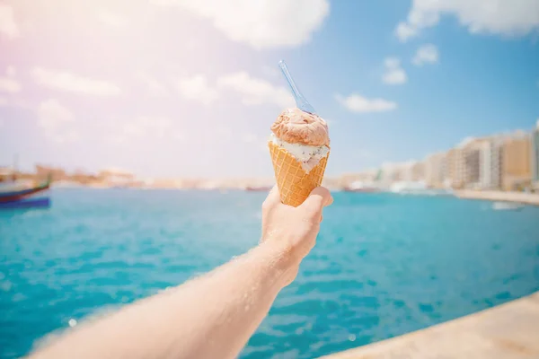人们用勺子把冰淇淋放在圆锥里,与蓝色的大海相映成趣. 放松的概念 — 图库照片
