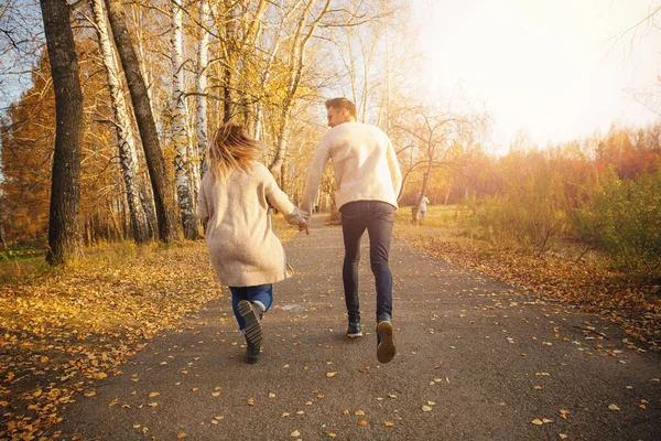 Glückliches verliebtes Paar läuft durch Herbstwald, Männerlächeln wirft Ahorngelbe Blätter — Stockfoto