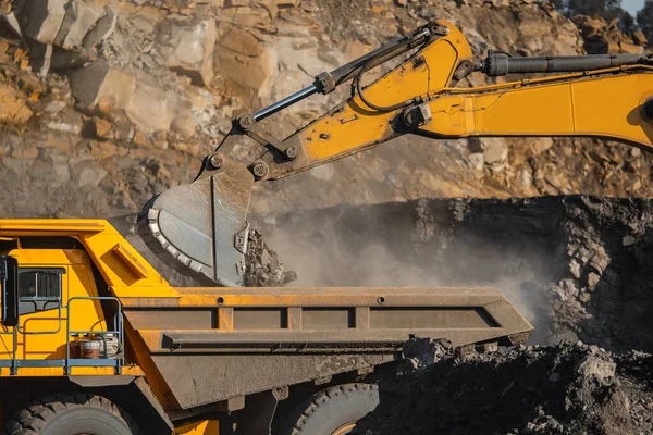 Open pit mine industry, excavator loading coal on big yellow mining truck for anthracite