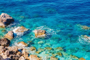 Arkaplan turkuvaz su denizi taşlı, şeffaf tabanlı.