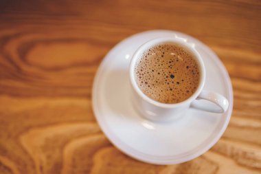 Beyaz seramik bardakta espresso kahvesi ahşap arka planda, Türk kumunda hazırlanıyor.