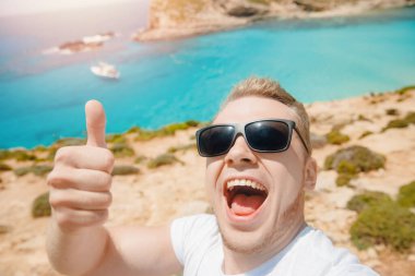 Erkek turist güneş gözlüğü sahilde fotoğraf çekiyor Mavi Göl Comino Malta