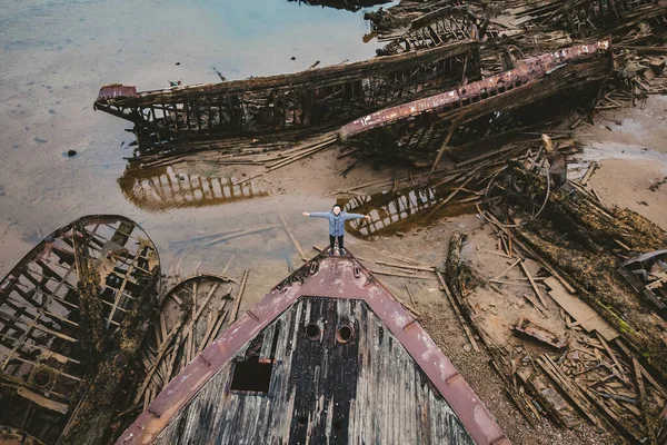Turista se dívá na hřbitov starých dřevěných lodí Teriberka, Murmansk region, Rusko. Letecký pohled shora — Stock fotografie