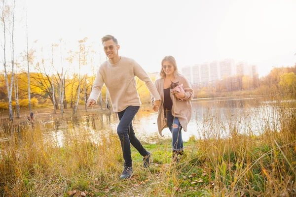 Glückliches verliebtes Paar läuft durch Herbstwald, Männerlächeln wirft Ahorngelbe Blätter — Stockfoto