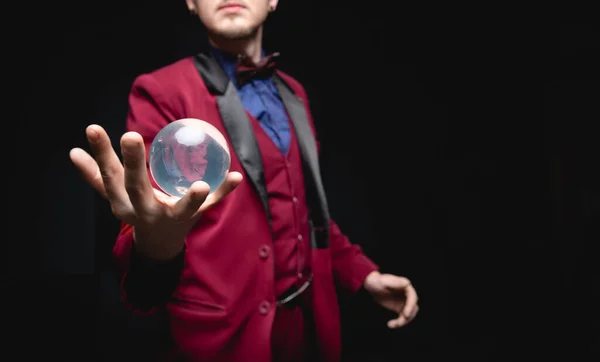 Illusionist magician shows levitation trick with ball in hands on black background — Stock Photo, Image