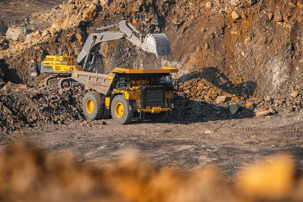 La excavadora hidráulica carga carbón en el cuerpo de un gran camión minero amarillo. Industria minera a cielo abierto para antracita — Foto de Stock