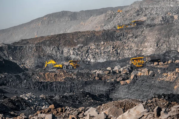 Industria minera a cielo abierto. Camión minero amarillo grande y excavadora para carbón que se mueve en la carrera de carretera — Foto de Stock