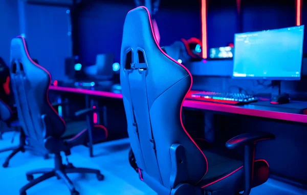 Професійна кібер-гральна студійна кімната з персональним комп'ютерним кріслом, клавіатура для потоку на фоні неонового розмивання кольорів. М'який фокус — стокове фото