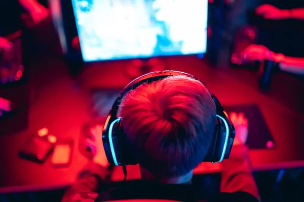 ヘッドフォン、赤と青でオンラインゲームコンピュータをプレイするぼやけた背景の専門的なゲーマーのトーナメント — ストック写真