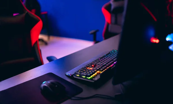 Χώρος εργασίας για επαγγελματίες gamer σε παιχνίδια ηλεκτρονικών υπολογιστών, online τουρνουά, άνετη καρέκλα, πληκτρολόγιο με οπίσθιο φωτισμό, οθόνες, μπλε και κόκκινο φόντο — Φωτογραφία Αρχείου
