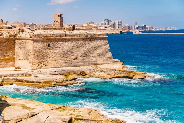 해변의 푸른 바 다에 벽돌 바위로 만들어 진 고대의 돌로 만든 몰타 요새 발레타 시가 보인다 — 스톡 사진