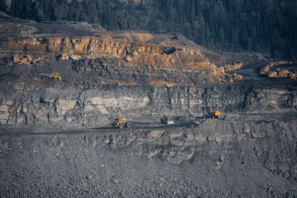 Open mine of gold, diamonds, coal. Industrial landscape with large yellow dump trucks and excavators