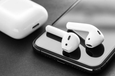 Kablosuz kulaklıklar, beyaz kulaklık depolama ve şarj kutusu, lüks siyah arka planda yeni bir telefon.